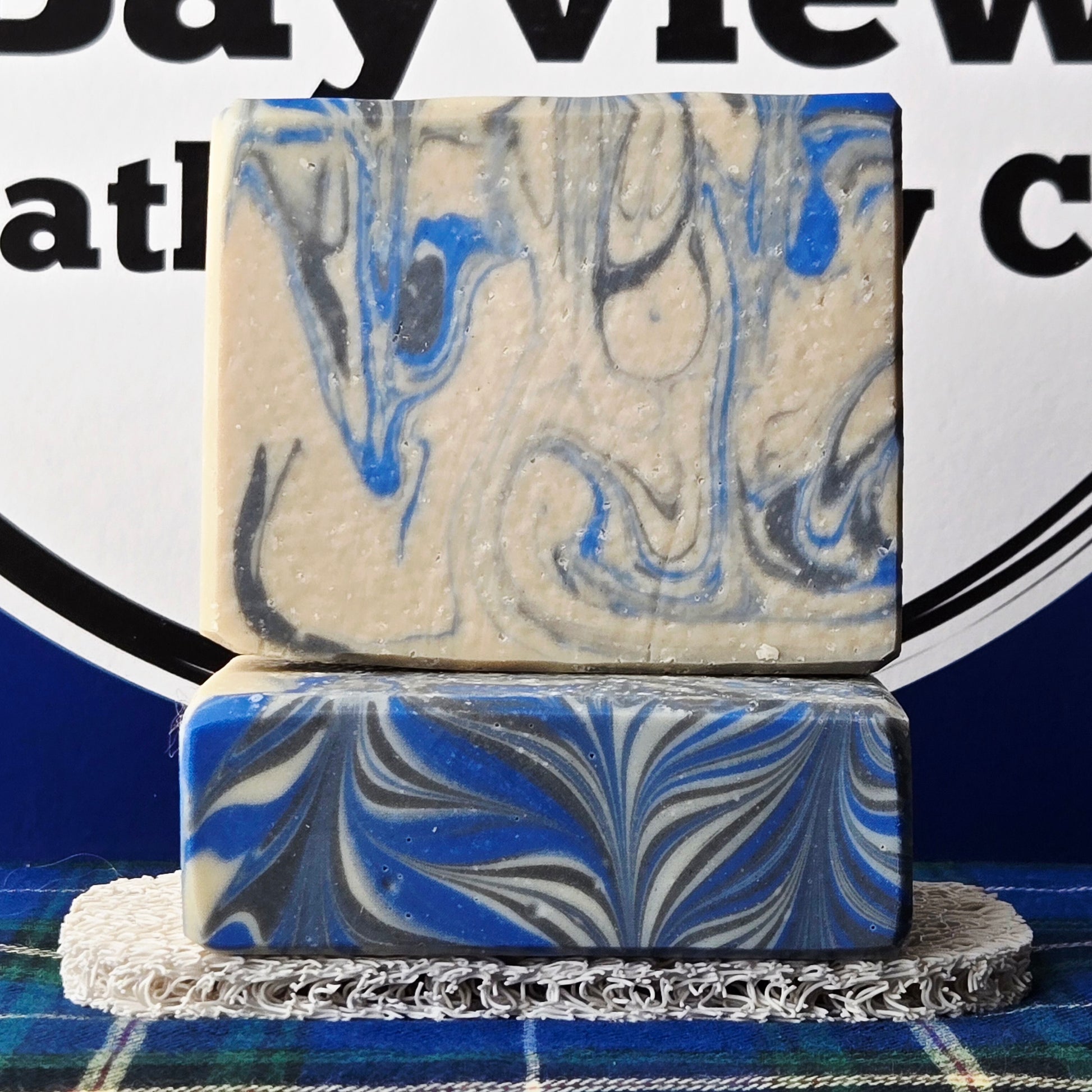 Two marbled soap bars stacked on a stand with a blurred background